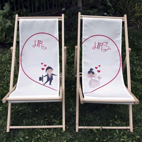 Mr. & Mrs. Hochzeits-Liegestühle mit Classic Herz-Motiv nebeneinanderstehend auf grünem Rasen im Garten.