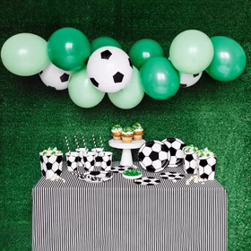 Komplett dekorierter Fußball-Partytisch mit Ballongirlande, Tellern, Bechern und Servietten.