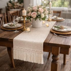Beiger Tischläufer im Boho-Style mit dekorativer Stickerei und cremefarbenen Fransen auf weißem Hintergrund.