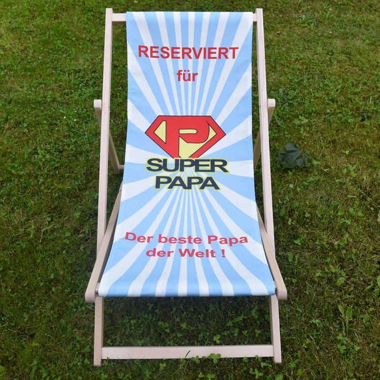 Liegestuhl mit Motiv Super-Mama und Super-Papa von Vorne im Gras stehend