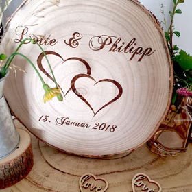 Personalisierte Baumscheibe mit Blumen und Deko-Herzen verziert.