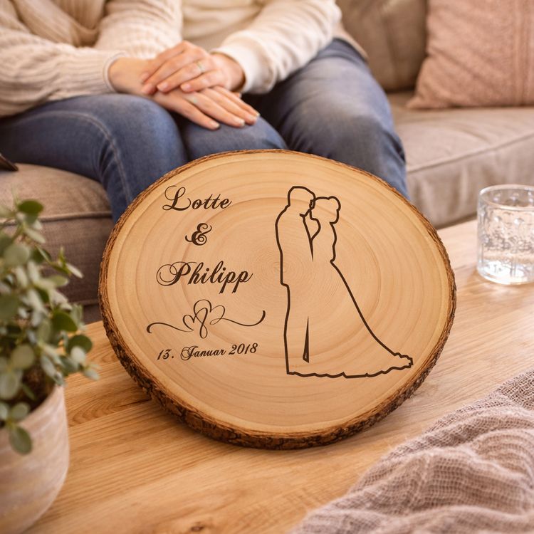 Baumscheibe mit Gravur 30 cm Brautpaar Namen und Datum Hochzeit Jahrestag Braut und Bräutigam halten eine personalisierte Baumscheibe mit Hochzeitsgravur während der Zeremonie, im Hintergrund Blumen und Hochzeitsgesellschaft.
