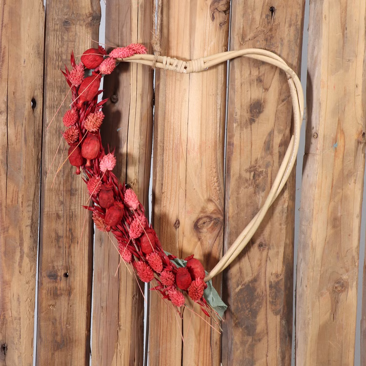 Rattan-Herzen 2er Set Natur 38 & 33 cm Deko-Herzen zum Basteln SALE Hochzeit Dekoration Bastelbedarf Türdeko Geschenk Großes Rattan-Herz hängt an einer Holzwand und ist dekorativ mit roten Trockenblumen geschmückt.