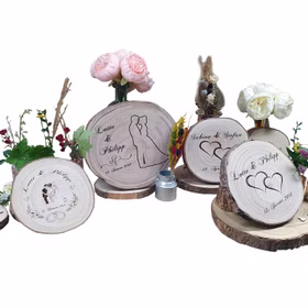 Mehrere dekorative Baumscheiben mit individueller Gravur, Blumen und Trockenblumen als Geschenkideen für Hochzeit und besondere Anlässe.