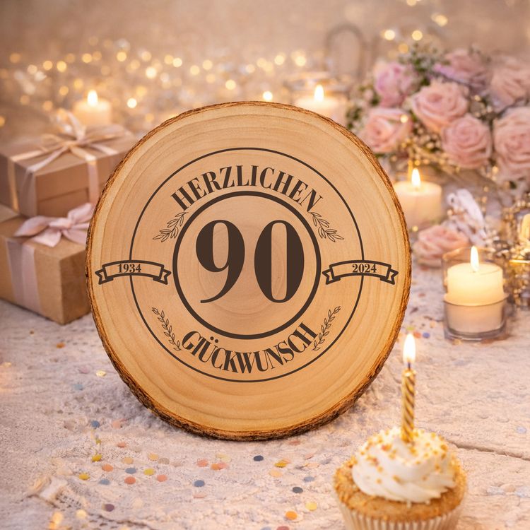 Baumscheibe Herzlichen Glückwünsch mit Wunschzahl-Gravur 30 cm Geburtstag Glückliche ältere Frau mit Familie bei der Geburtstagsfeier, im Vordergrund eine Baumscheibe mit Gravur „Herzlichen Glückwunsch 90“.