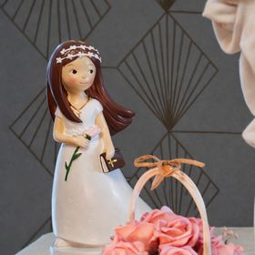 Figur Kommunion Mädchen im weißen Kleid mit langen, braunen Haaren Blume und Bibel in der Hand und mit weißem Blumenkranz im Haar vor weißem Hintergrund.