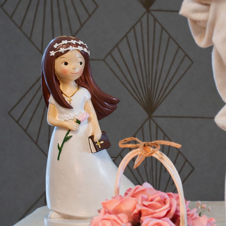 Figur Kommunion Mädchen im weißen Kleid mit langen, braunen Haaren Blume und Bibel in der Hand und mit weißem Blumenkranz im Haar vor weißem Hintergrund.