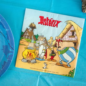 Asterix Serviette mit Motiv aus dem gallischen Dorf neben Zaubertrankkessel und Obelix auf türkisfarbener Tischdekoration.
