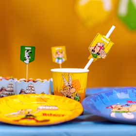 Asterix & Obelix Partybecher mit Comicmotiv auf Geburtstagstisch neben Tellern und Dekoration.