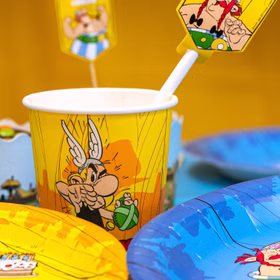 Asterix Partybecher mit Papierstrohhalm und Partygeschirr auf dekoriertem Geburtstagstisch.
