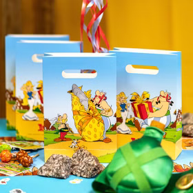 Hellblaue Geschenktüten mit Asterix- und Obelix-Motiven als dekorative Partyverpackung auf festlich gedecktem Tisch.