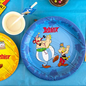 Asterix & Obelix Pappteller in Blau mit Partymotiv auf gedecktem Geburtstagstisch neben Bechern und Dekoration von Oben.