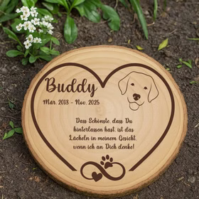 Personalisierte Baumscheibe als Hundegedenktafel im Garten auf Erde mit kleinen Blumen.