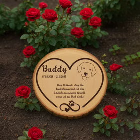 Personalisierte Baumscheibe mit Hundemotiv als Gedenkstelle zwischen roten Rosen im Garten.