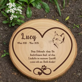 Personalisierte Baumscheibe als Gedenkstelle für eine Katze im Gartenboden.