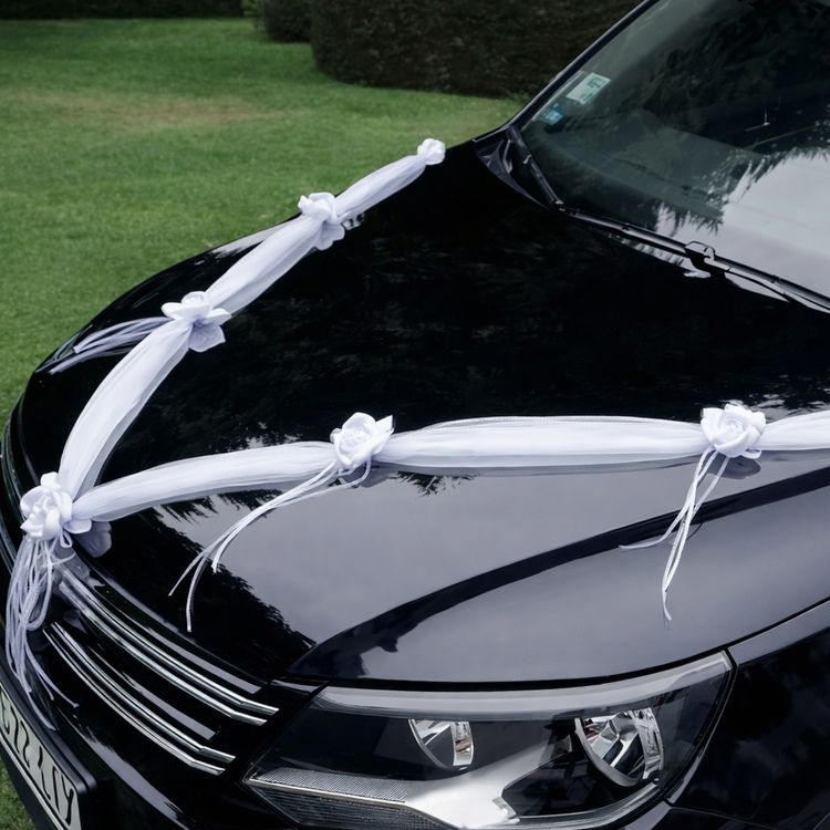 Detailansicht der weißen Hochzeitsgirlande mit Rosenblüten entlang der Motorhaube eines Fahrzeugs.