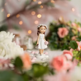 Kommunionfigur Mädchen mit Blumenstrauß als Tischdekoration bei einer festlichen Kommunion- oder Taufdekoration mit Blumen und Kerzen.