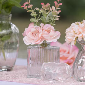 Mini Glasvasen-Set 6er Rosa Grün Klar Tisch-Deko Hochzeit Geburtstag gedeckter Tisch Blumenvase kleine Glasvase Dekoration Events Transparente Mini-Glasvase mit zarter Kunstblume und strukturierter Glasoberfläche auf dekorativ gedecktem Tisch.