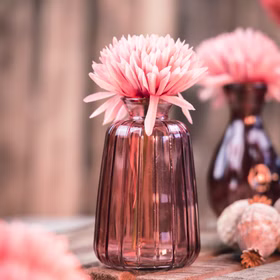 Rosa Glasvase Verone mit großer rosa Blüte auf rustikaler Holzfläche, dekoriert im romantischen Vintage-Stil.