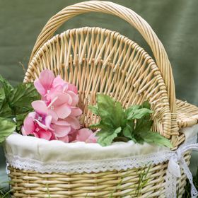 Geflochtener Picknickkorb aus Weide mit geöffnetem Deckel und hellem Stoffeinsatz mit Spitze.