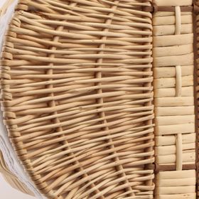 Geflochtener Picknickkorb aus Weide mit geöffnetem Deckel und hellem Stoffeinsatz mit Spitze.