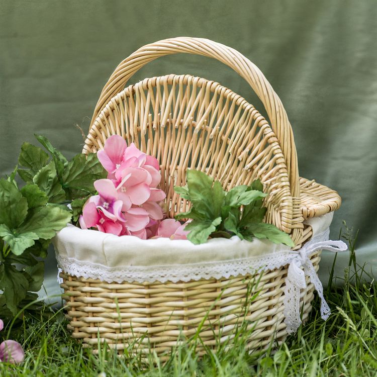 Geflochtener Picknickkorb aus Weide mit geöffnetem Deckel und hellem Stoffeinsatz mit Spitze.