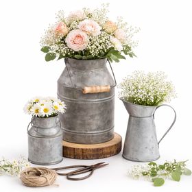 Milchkannen 3er-Set als Vase mit zarten Blumenarrangements auf weißem Hintergrund – elegante Vintage Tischdeko für Hochzeit oder Geburtstag.
