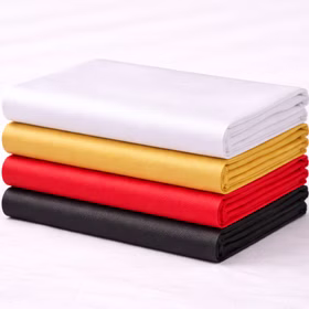 Gefaltete Teppichläufer aus Polyester-Vlies in Weiß, Gold, Rot und Schwarz übereinander auf weißem Hintergrund.