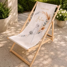 Liegestuhl für die Braut mit Name Julia, Hochzeitsdatum und floraler Boho-Illustration auf heller Terrasse.