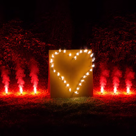 Lichterbild Brennendes Herz mit rotem Bengalfeuer Feuerwerk Feuerbild Geschenkidee Geburtstag Goldene Hochzeit Jubiläum Verlobung Lichterbild in Herzform mit Bengalfeuern auf einer Wiese bei Nacht.