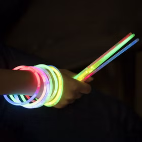 Bunte Knicklichter als leuchtende Armbänder und Leuchtstäbe im Dunkeln für Party, Festival, Camping und Nachtwanderung bei Nacht.