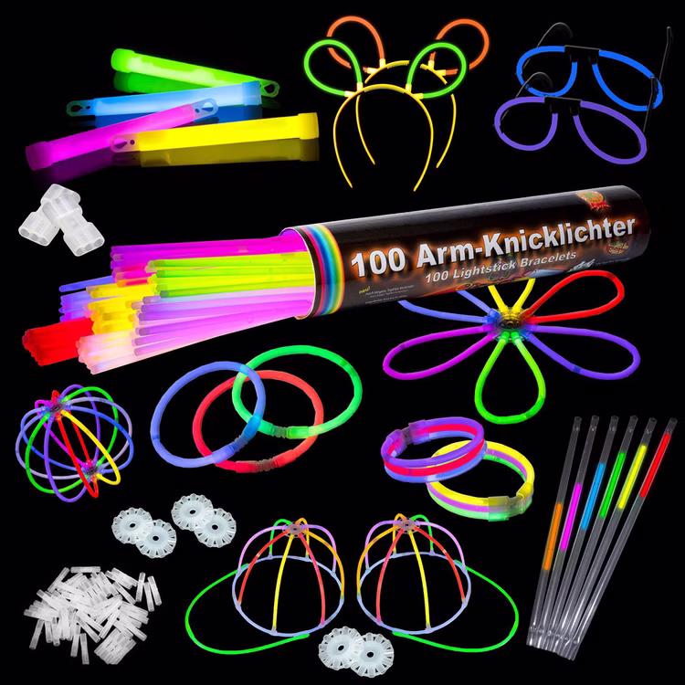 Knicklichter Party Box Leuchtzubehör im Dunkeln Leuchtendes Zubehör der Party Box auf schwarzem Hintergrund mit Brillen, Hasenohren, Base Caps, Armbändern und Strohhalmen.